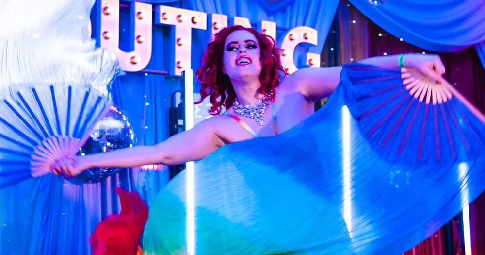 An image from The Outing festival showing a woman dancing on stage with two fans.