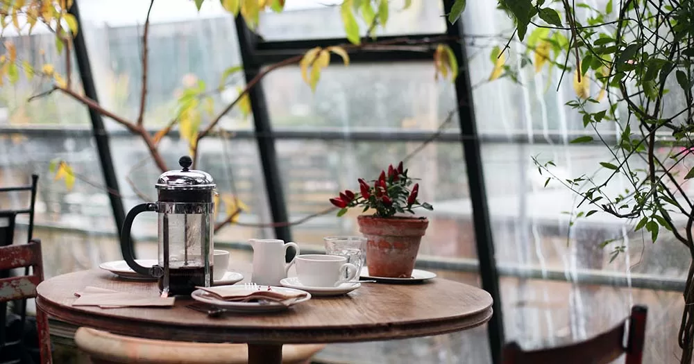 This article is about taking care of your mental health during winter. The photo is of a coffee table with french press and flowers.