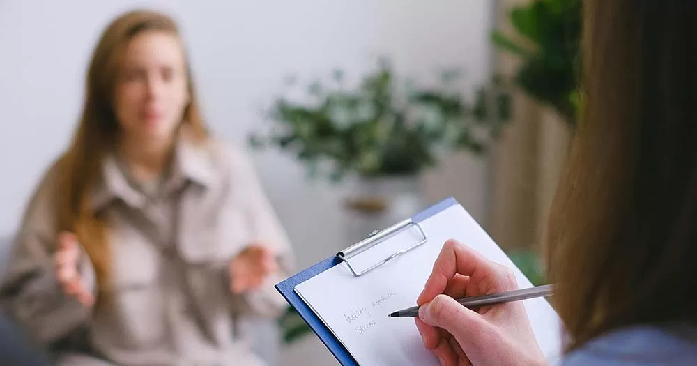 Photo of clipboard and teen talking, article is about a new transgender clinic