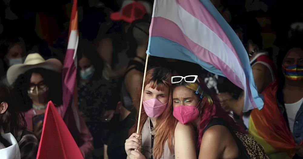 This article is about the murders of three trans people in Mexico. In the photo, people at a protest in Mexico, waving a trans flag.