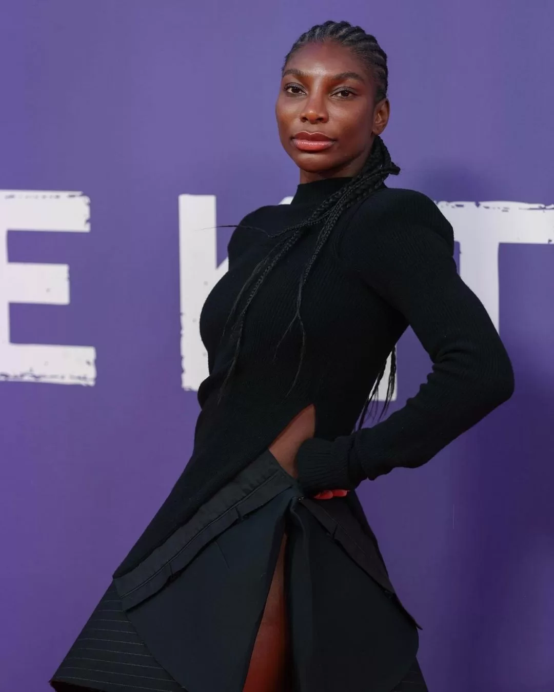 Photograph of Michaela Coel, one of the asexual and aromantic celebrities listed in the article, wearing a black dress posing in front of purple background