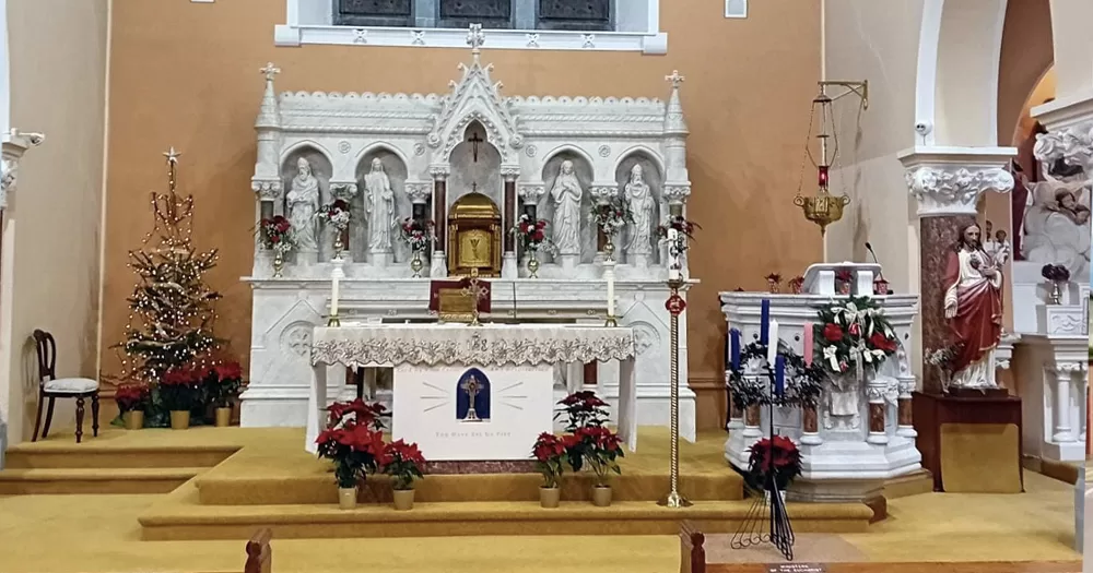 Interior of St. Joseph's Church, where a special ceremony for a Cork school was held, with the altar, a yellow carpet ans many green flowers.