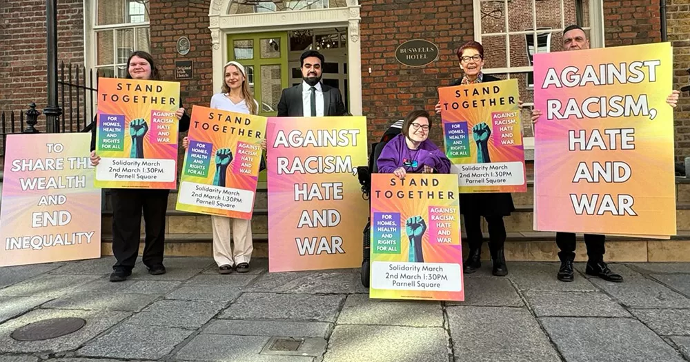 Representatives of various groups taking part in the Stand Together solidarity march in Dublin posing for a photo. The group of six people hold various signs promoting the march.