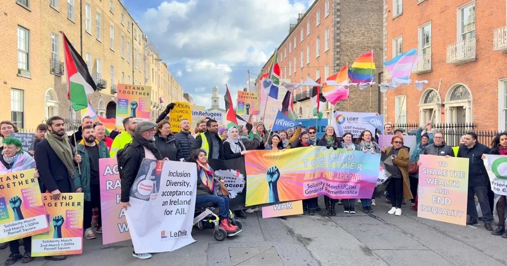 Photocall for the Stand Together march, with people standing with banners and flag in Dublin.