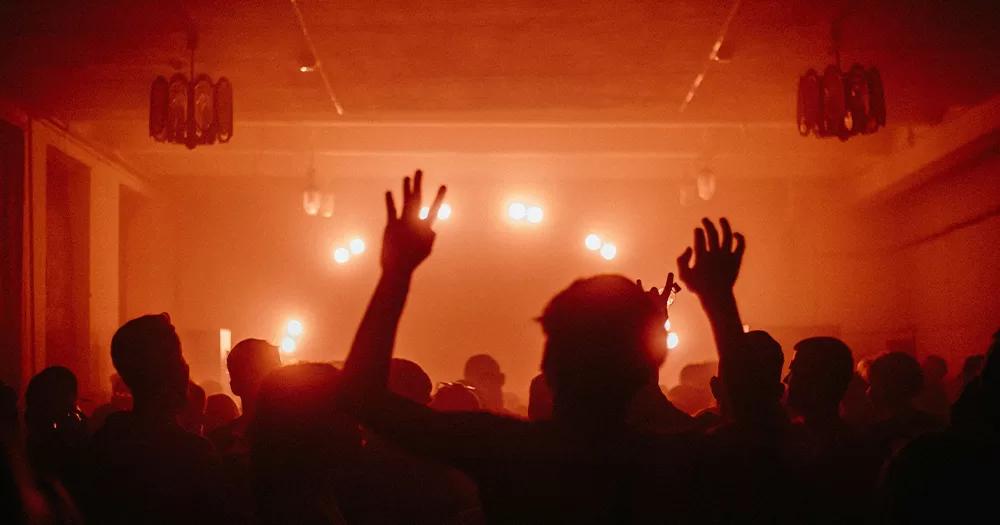 This article is about LGBTQ+ history in Australia. In the photo, people dancing in a club with red lights.