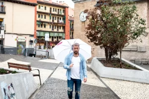 Javier Conde holding a white umbrella on the streets on Madrid for an Elska photoshoot. 