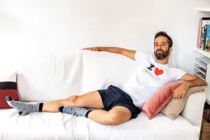 Luis G sitting on a sofa wearing a shite shirt that says "I <3 Benidorm" for Elska photoshoot. 