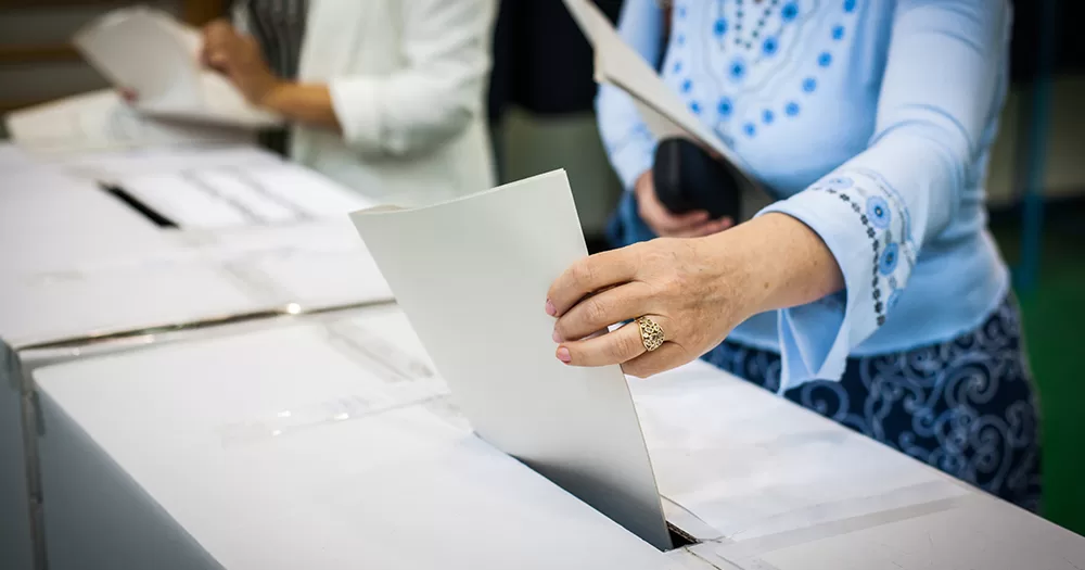 This article is about people voting in two referendums in Ireland. In the photo, the hand a of a person inserting a ballot card in a box.