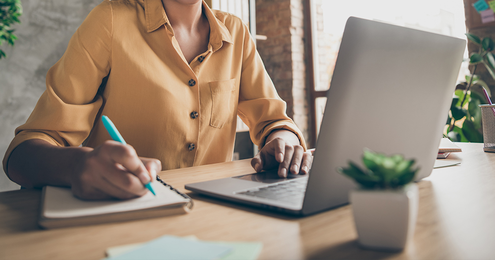 GCN is hiring a Digital Marketer and an Administrative Assistant. In the photo, the hands of a person working at a laptop.