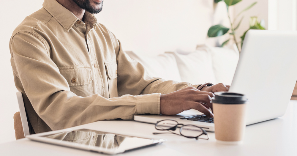 GCN is hiring a Digital Marketer and an Administrative Assistant. In the photo, the hands of a person working at a laptop.