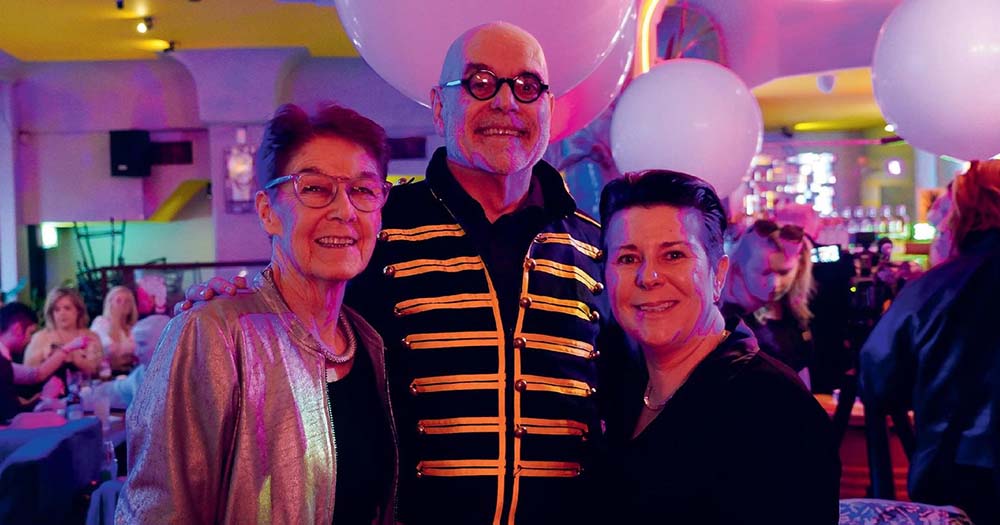 Group photo of three people standing together at queer prom