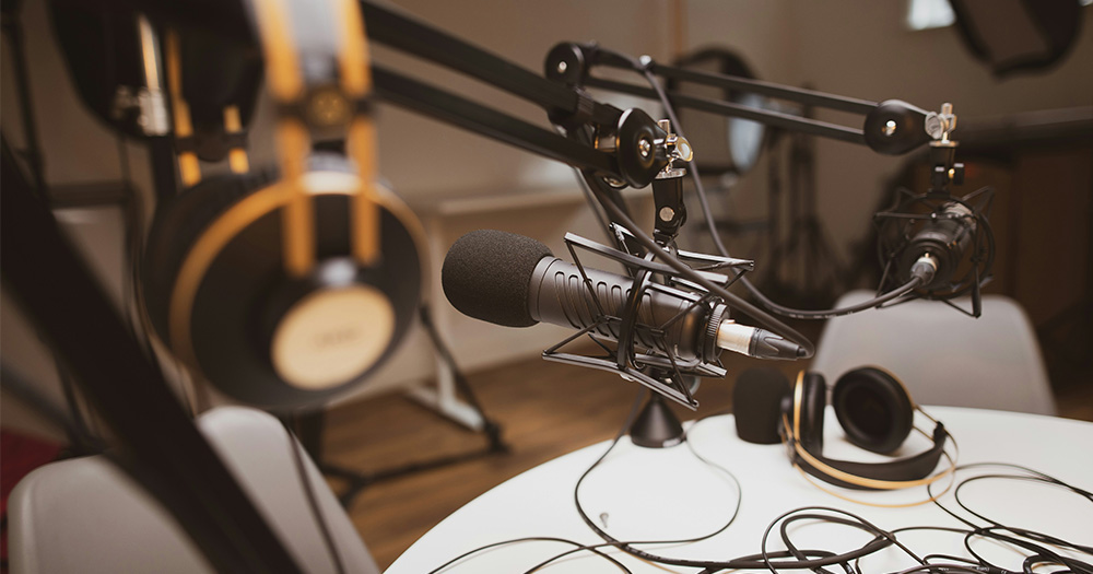 This article is about Dublin Digital Radio's Queering the Airwaves. The image shows a microphone is set up next to a pair of headphones in a recording studio.