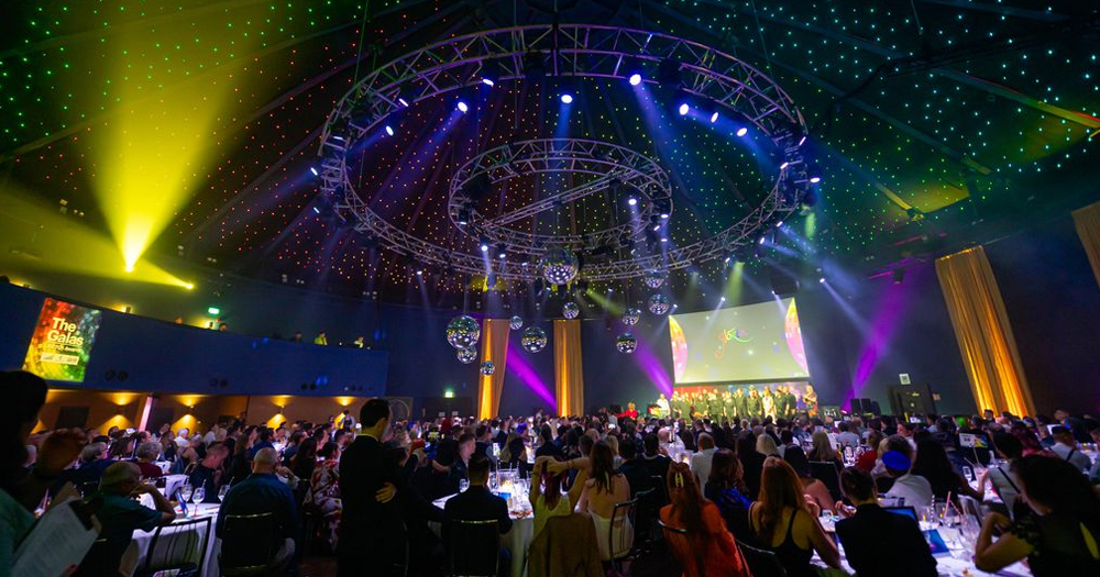 Photos of the GALAS Awards, with nominations now open for the 2024 ceremony. People are sitting at tables in a dark room with colourful lights.