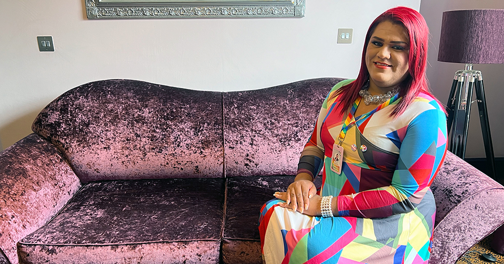 Trans activist Jennifer Cordova from Honduras, sitting on a purple sofa, wearing a colourful dress.