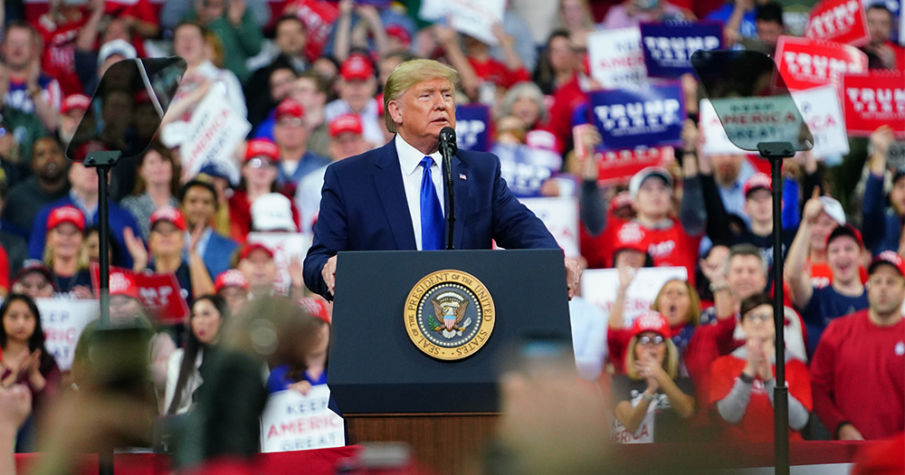 Trump delivers speech from podium to a crowd of rally goers.