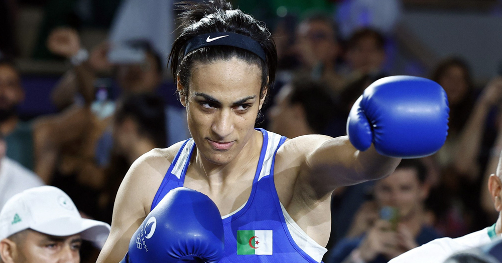 Olympic boxing champion Imane Khelif, who filed a legal complaint for harassment , posing in her blue boxing uniform and gloves on a ring.