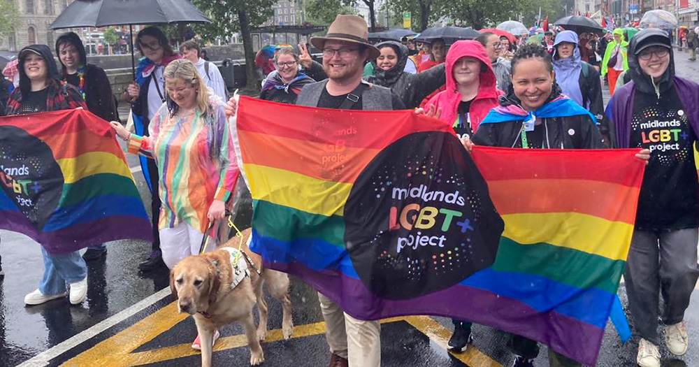 Laois Pride 2024 organisers Midlands LGBT+ Project march in a parade holding a rainbow flag with their logo on it.