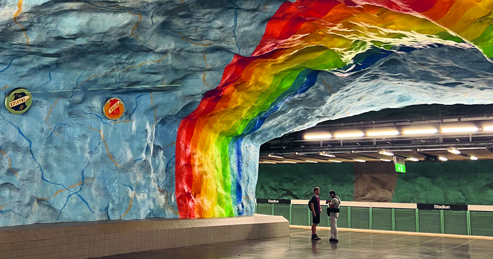 An underground station in Stockholm with an LGBTQ+ Pride flag painted on the ceiling.