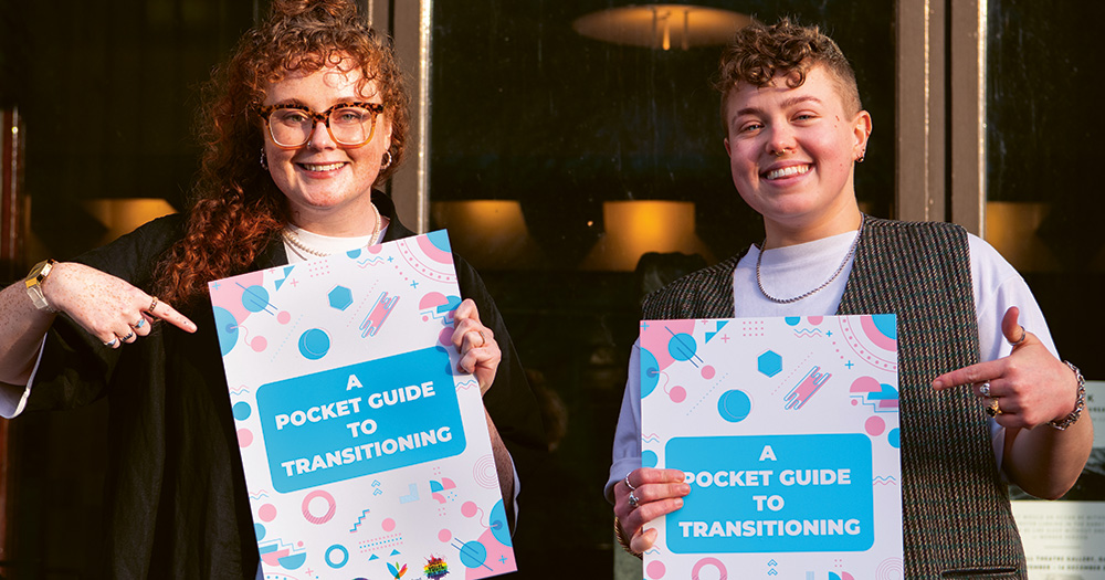 Two people pose with the document entitled 'A Pocket Guide To Transitioning'.