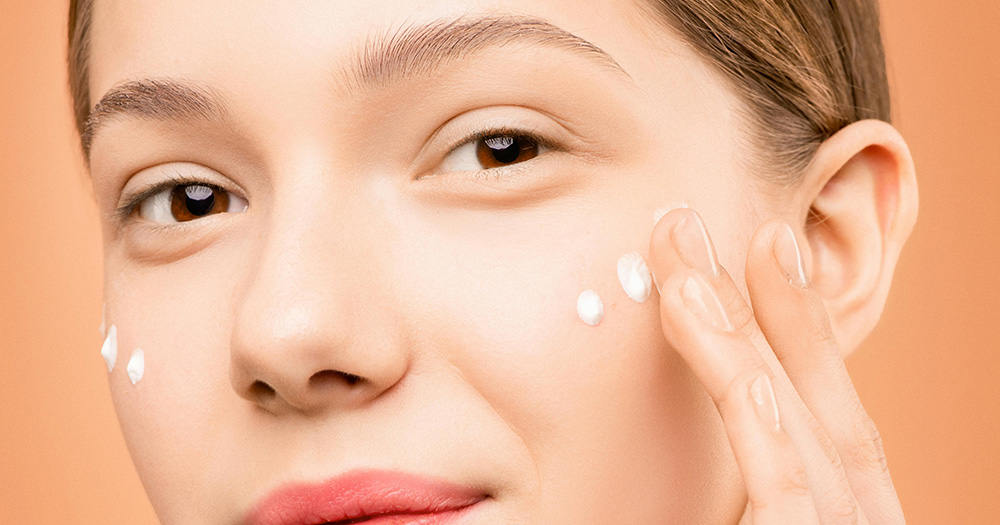 This article is about natural wellbeing remedies. The image is a close up of a woman's face as she applies face cream.