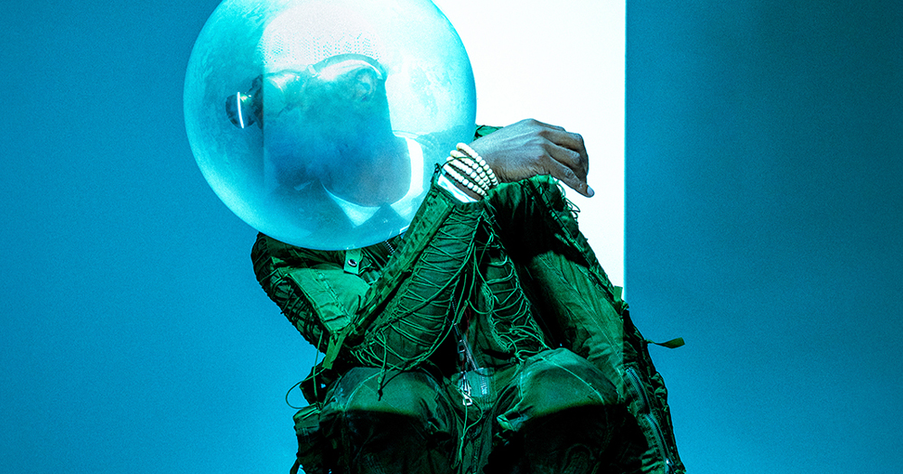 Image from a show featured at Dublin Theatre Festival 2024 portraying a man in a green suit with a bubble on his head.