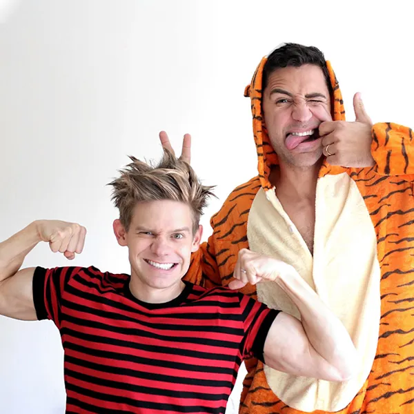 This picture shows two men in Calvin & Hobbes costumes. One is wearing a black and red striped shirt, the other one a tiger onesie.