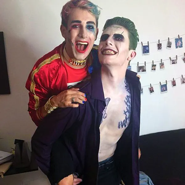 This queer couple costume idea for Halloween is about Harley Quinn and the Joker, so the two men in the picture are dressed up as those characters wearing makeup and having their hair dyed.