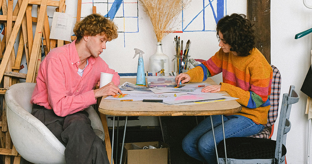 This article is about the WOWTE Artist Residency Awards 2024. The image shows two artists sitting at a table and drawing.