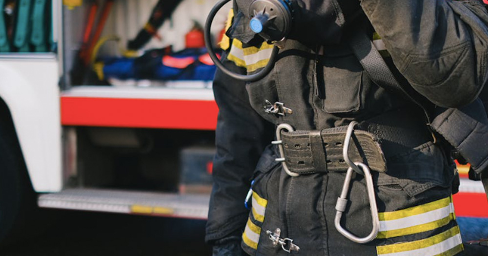 This article is about a firefighter harassment case. The image shows a firefighter standing in front of a fire truck.