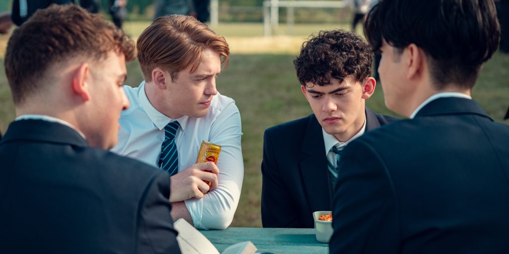 Screenshot from Heartstopper TV show, created by Alice Oseman. It shows four characters sitting at a table.