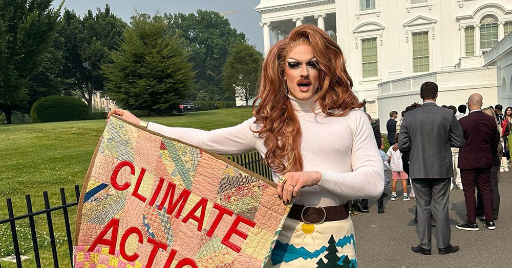 Drag artist Pattie Gonia, whose image was recently used in a Trump ad, in full drag holding a banner that reads 'climate action now'.