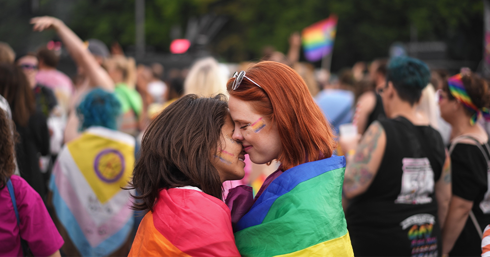 This article is about a resolution on the rights of queer women. In the photo, two women kissing in the middle of a Pride parade.