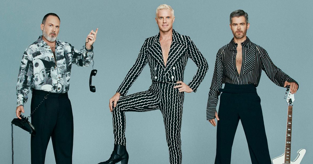 Scissor Sisters members, who have announced a reunion tour, posing for the camera wearing black and white clothes with a grey background.