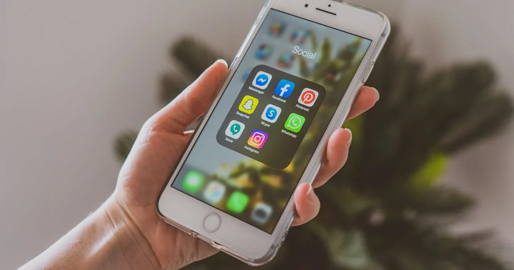 This article is about new Irish social media rules. In the photo, a hand holding a phone with social media apps on the screen.