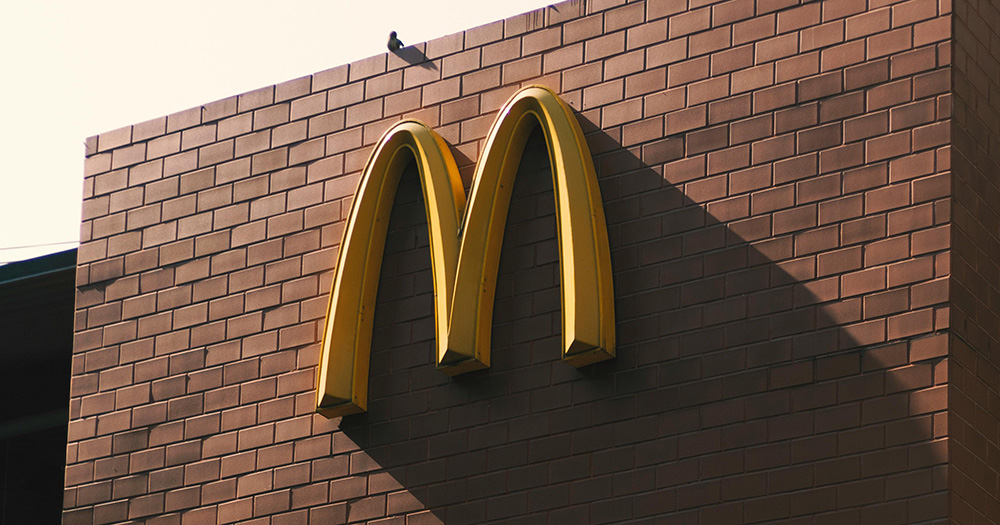 An image of the McDonald's signature golden arch logo on the side of a red brick building.