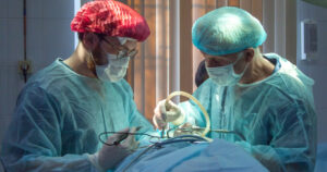 This article is about HIV positive organ donors in the US. In the photo, two surgeons operating on a patient.