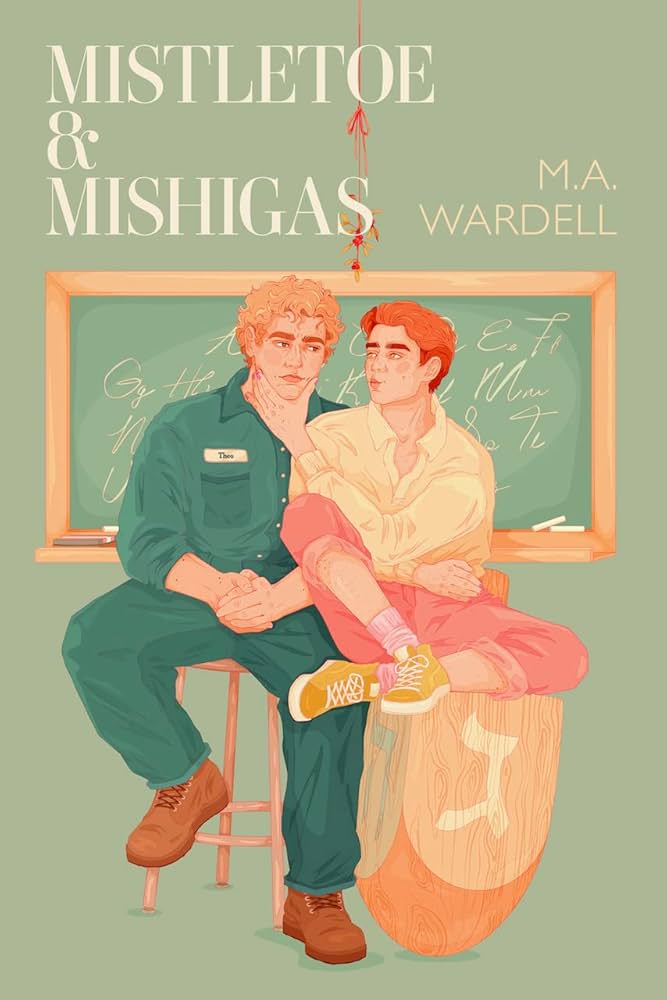 the cover for holiday romance novel mistletoe and mishigas. It shows two men sitting, one on a desk the other on a dradel. 