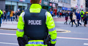 This article is about PSNI allowing officers to display pronouns on their badges. In the photo, a police officer's back while patrolling the streets of Belfast.