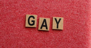 This article is about reclaiming language to combat homophobia. The image shows three wooden blocks with letters GAY.