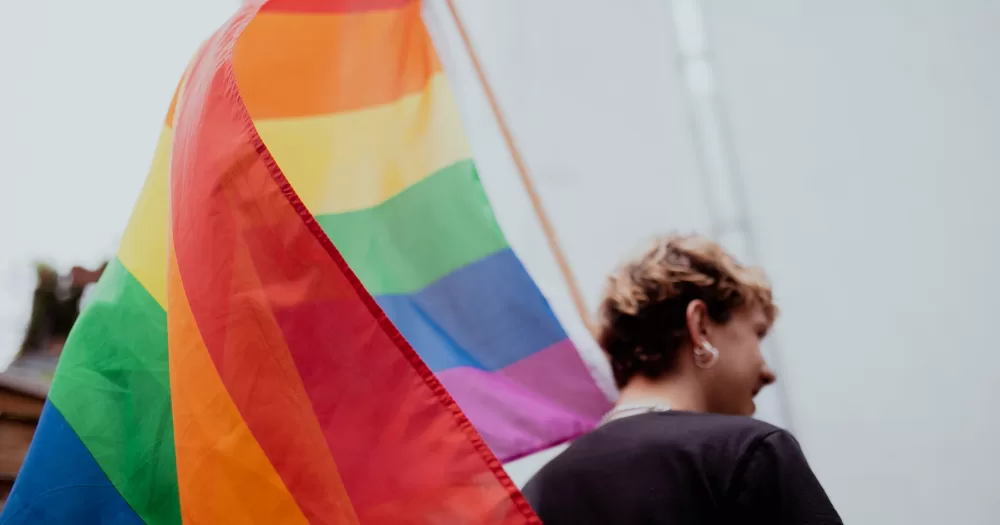A person holds a Pride flag, this article covers the recent GLAAD report Anti-LGBTQ+ incidents in the US