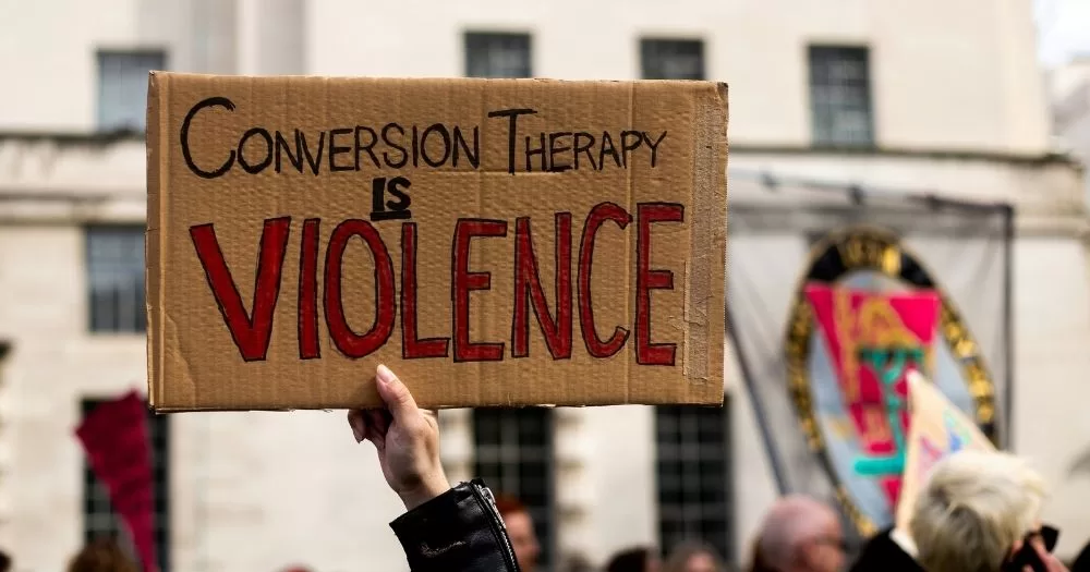 A protestor holds a sing that says "Conversion therapy is violence."