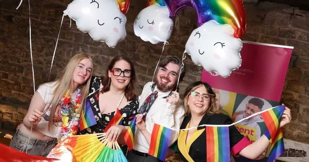 People hold rainbow flags and balloons as they celebrate at Belong To's award ceremony celebrating youth services working with LGBTQ+ youth.