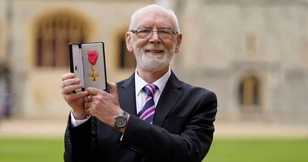 Martyn Butler holds his OBE in an outdoor setting.