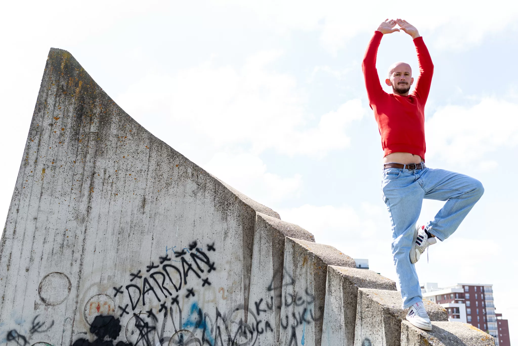 A man who poses in a piourette on a concrete slab in the city.