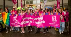 Belong To youth club celebrating Pride behind a large banner.They have recently been nomintaed for a community funding award