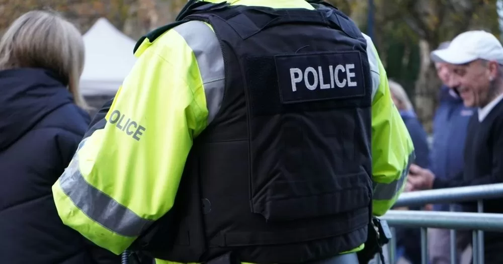 This article is about a man who was allegedly blackmailed on Grindr. In the photo, a police officer facing away from the camera wearing a uniform.