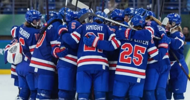 The US ice-hockey team, which includes several publicly LGBTQ+ athletes gather in a huddle on the ice.